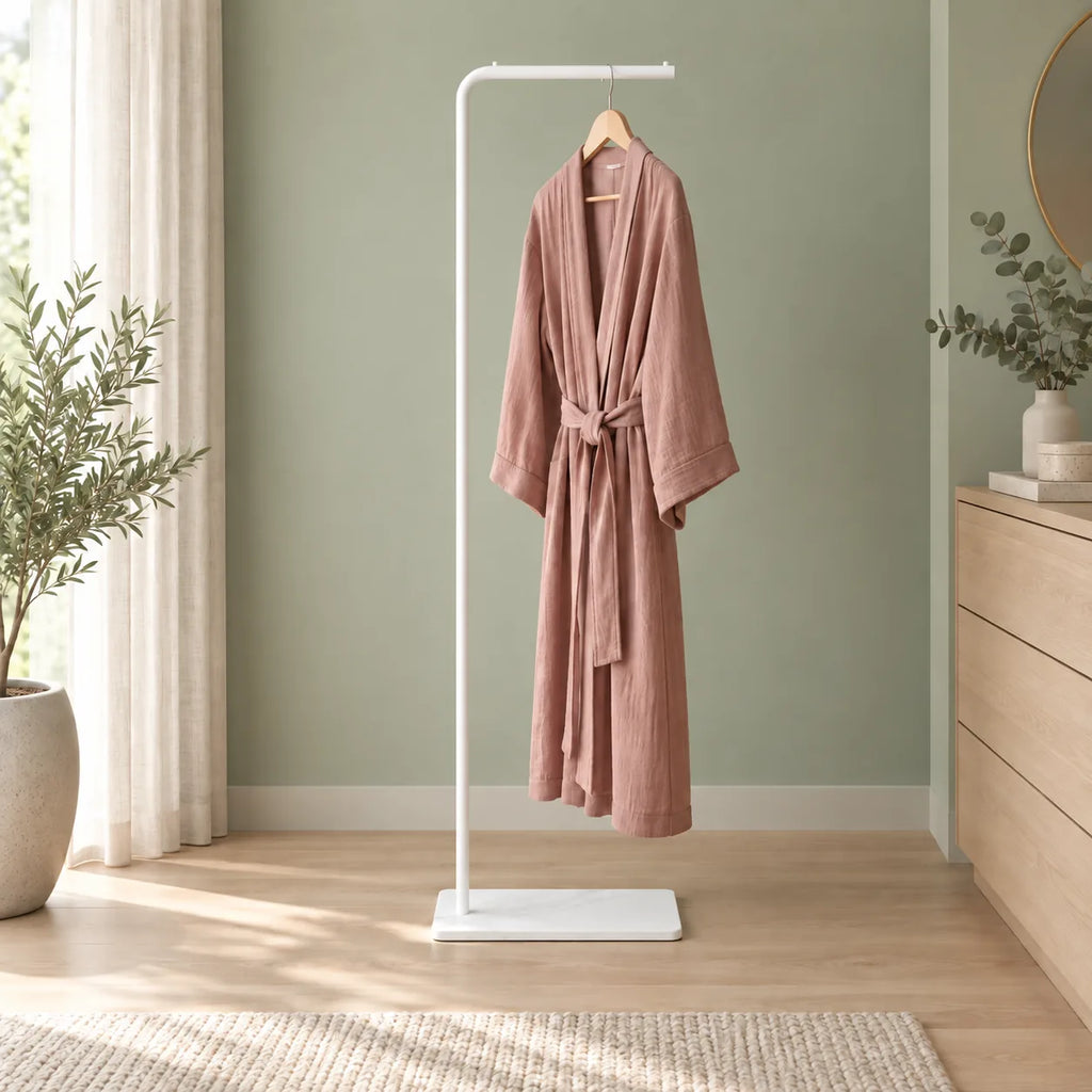 Porte-manteau valet blanc avec peignoir rose dans un dressing vert sauge