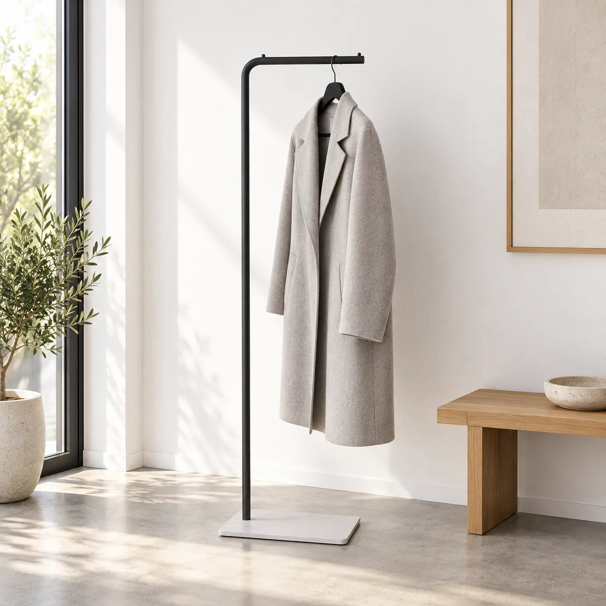 Porte-manteau valet noir avec manteau gris dans une entrée minimaliste
