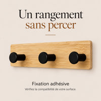 Patère adhésive en bambou naturel avec trois crochets noirs et conseil de vérifier la surface de pose.