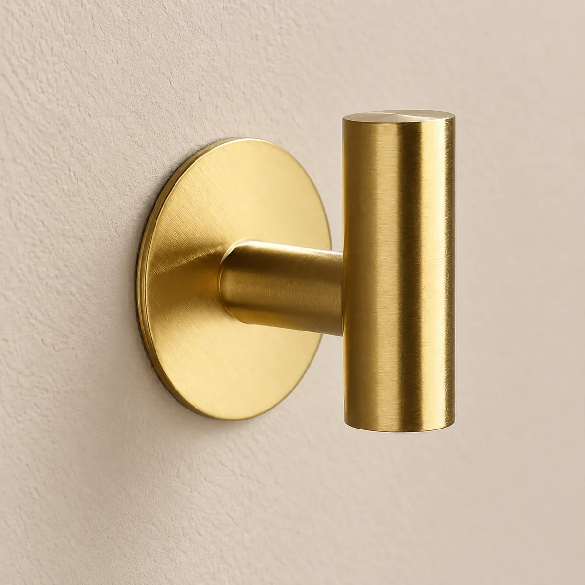 Patère design dorée en inox adhésive : détail de la base ronde fixée au mur