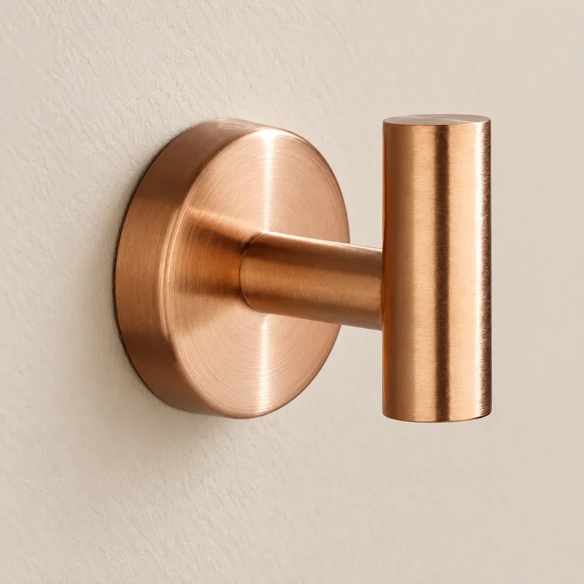 Patère design or rose en inox à vis : détail de la base ronde fixée au mur