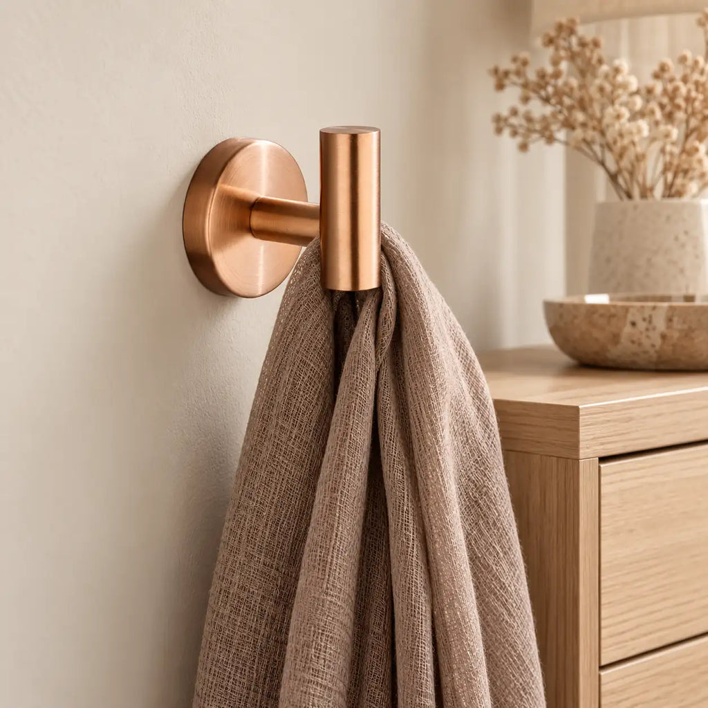 Patère design or rose en inox à vis : écharpe près d’un meuble