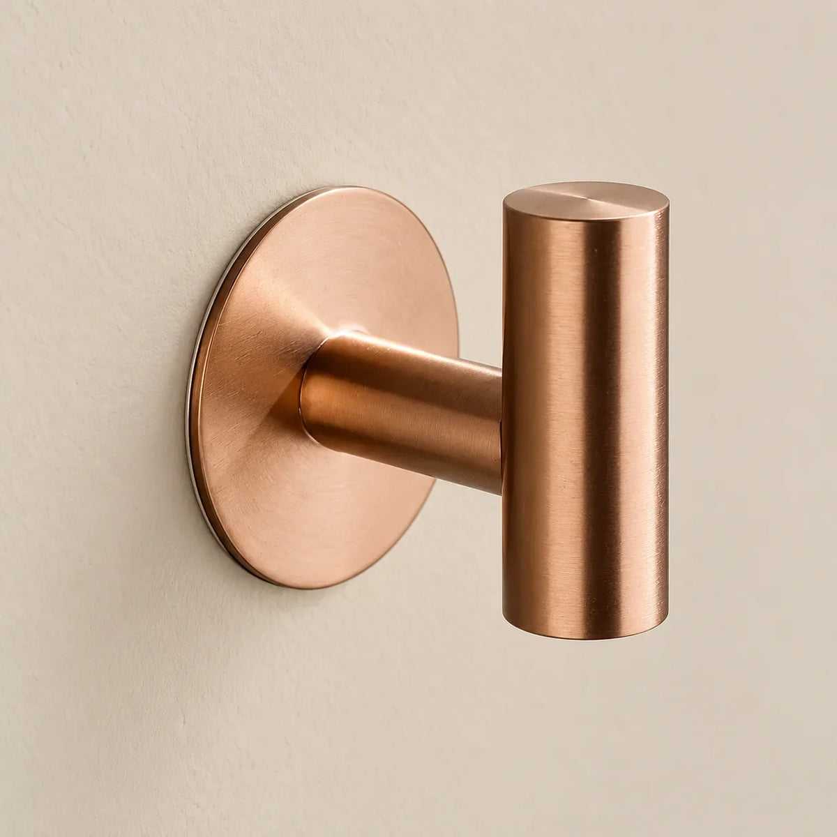 Patère design or rose en inox adhésive : détail de la base ronde fixée au mur