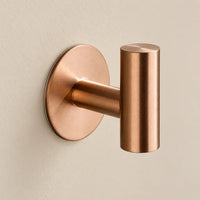 Patère design or rose en inox adhésive : détail de la base ronde fixée au mur