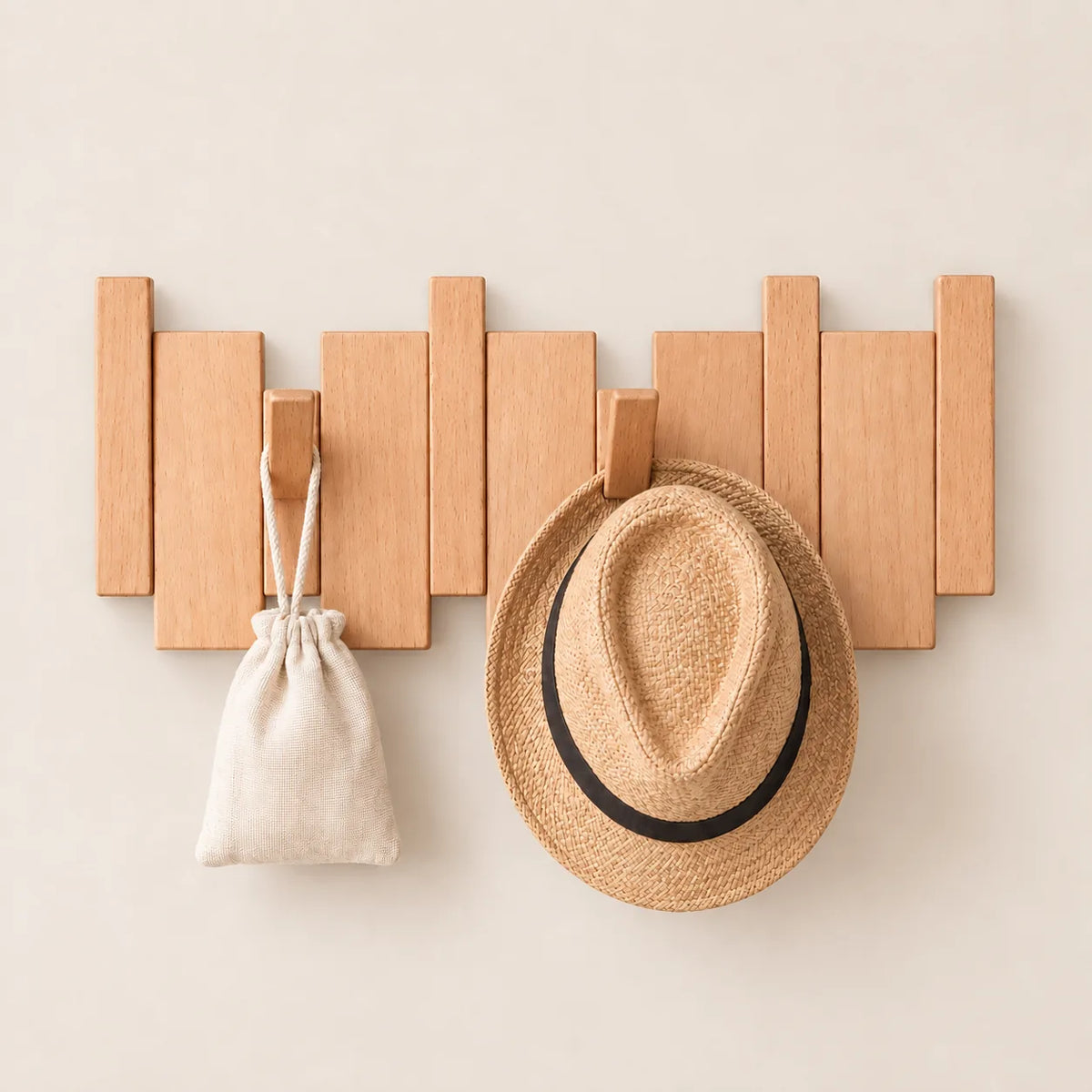 Patère hêtre naturel clair 4 crochets avec chapeau et petit accessoire suspendus.