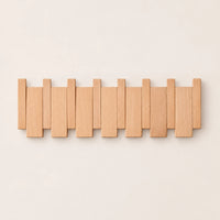 Patère murale en hêtre naturel clair, modèle 6 crochets piano, sur fond beige.