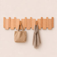 Patère murale en hêtre naturel clair, 8 crochets, avec sac et écharpe.